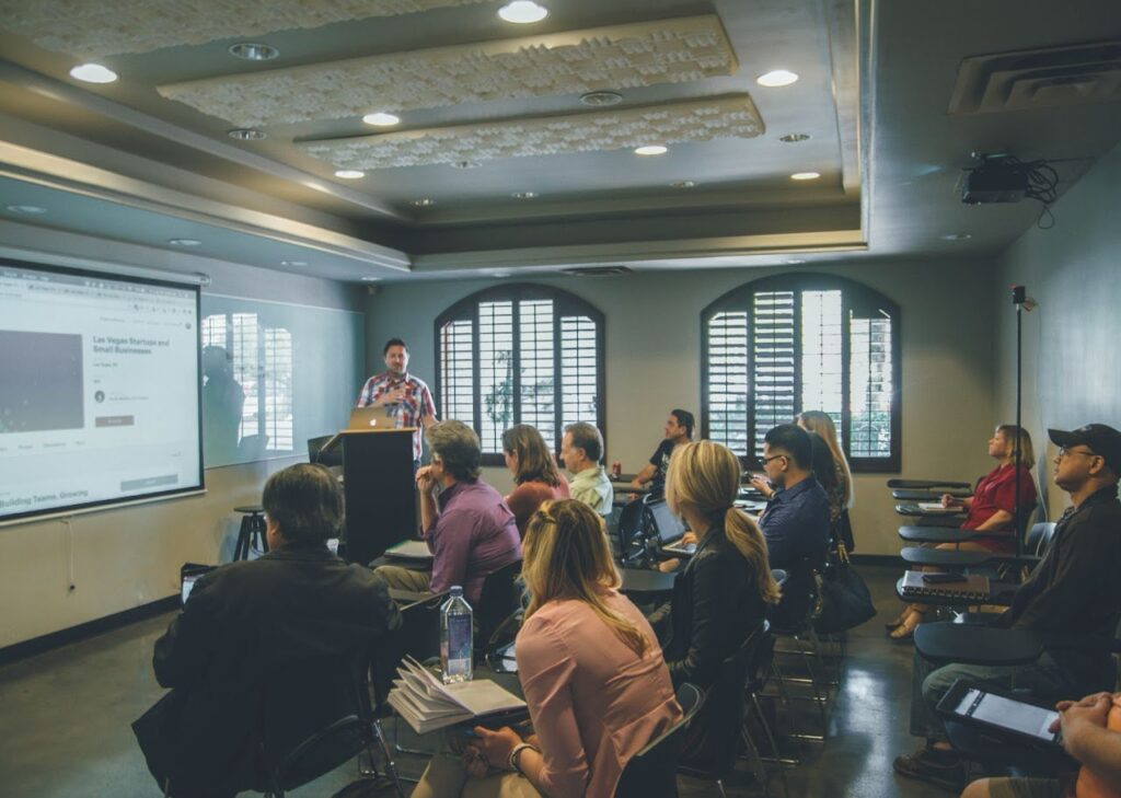 man speaking at a podium in front of a class