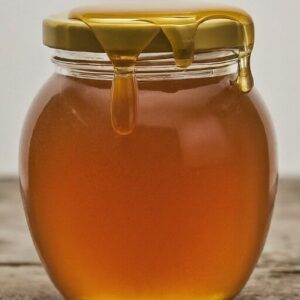 bee propolis infused honey jar with honey dripping from lid