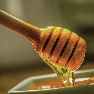 bee propolis infused honey dripping from honey dipper